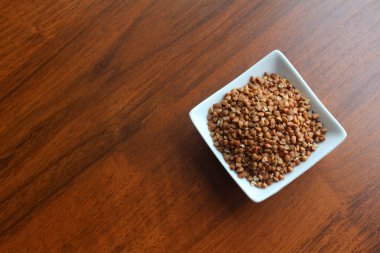 Beyaz kase ahşap bir masa üzerinde buğday taneleri ile ana sayfa görünümü.