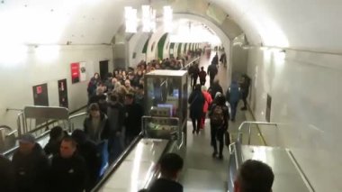 Metro istasyonundaki bir sürü insan yürüyen merdivene çıkıyor..