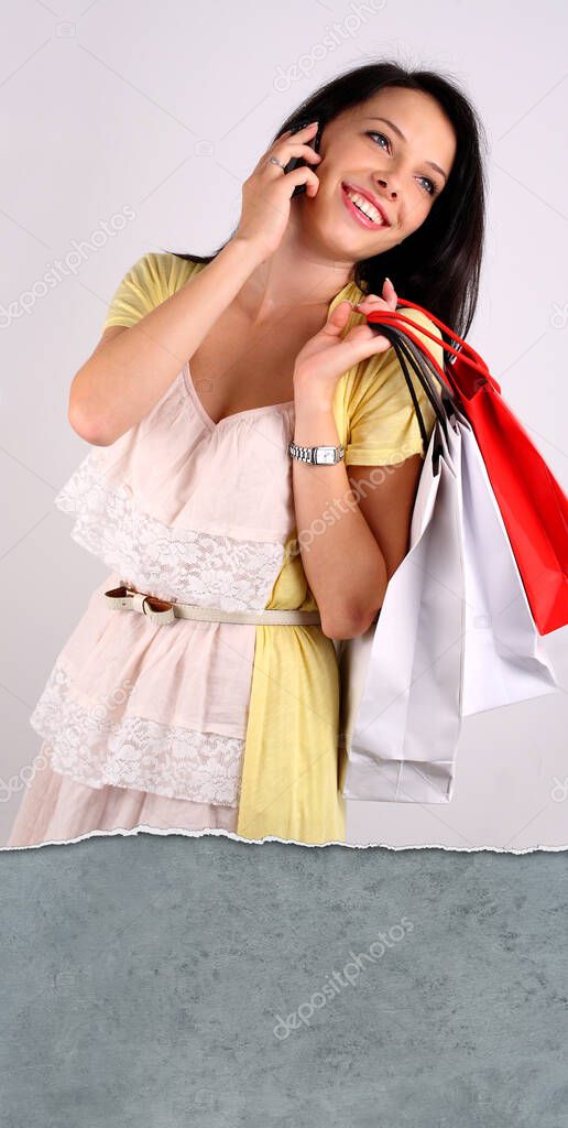 Young woman holding shoping bags, talking on the phone