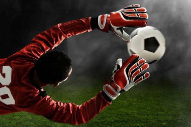 Futbol kalecisi topu yakalıyor.