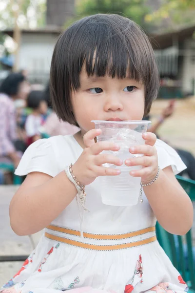 Dziecko dziewczyna wody pitnej w szklanym plastiku. — Zdjęcie stockowe
