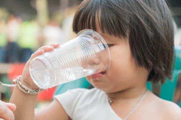 ガラスプラスチックで水を飲む子供の女の子. — ストック写真