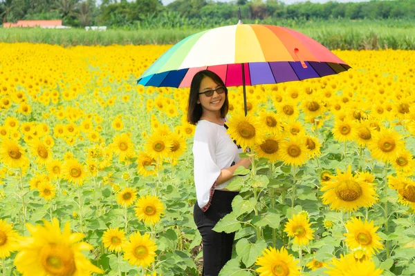 Vrouw die een paraplu in een zonnebloem veld vasthoudt. — Stockfoto
