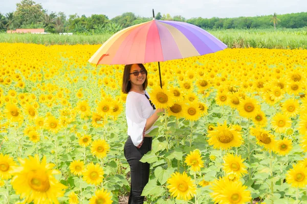 Vrouw die een paraplu in een zonnebloem veld vasthoudt. — Stockfoto