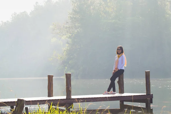 Женщина сидит на деревянном мосту — стоковое фото