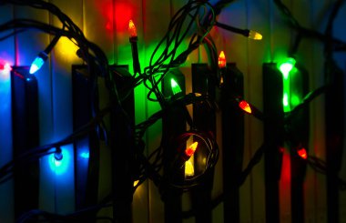 Çeşitli renklerde ışık karanlık bir arka plan üzerinde piyanoda bir Garland