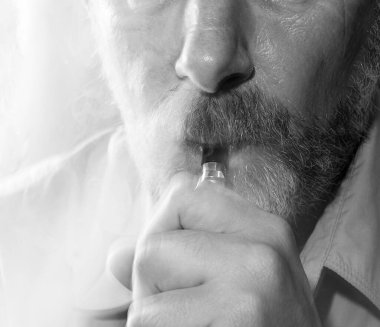 Hafif arka planda sigara içen bir adamın siyah-beyaz portresi