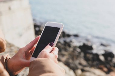 Kumsalda akıllı telefon kullanan güzel bir kadın.