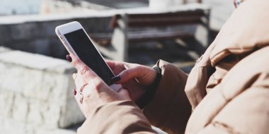 Kumsalda akıllı telefon kullanan güzel bir kadın.