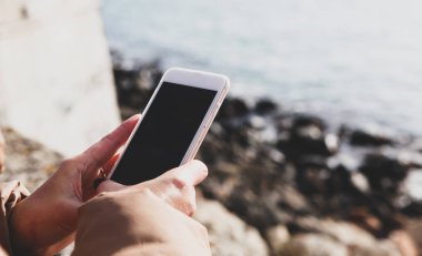 Kumsalda akıllı telefon kullanan güzel bir kadın.