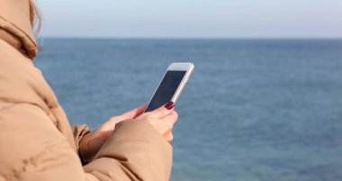 Kumsalda akıllı telefon kullanan güzel bir kadın.