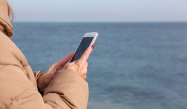 Kumsalda akıllı telefon kullanan güzel bir kadın.