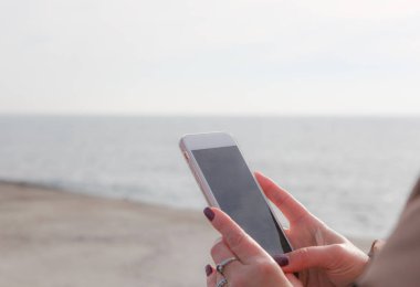 Kumsalda akıllı telefon kullanan güzel bir kadın.