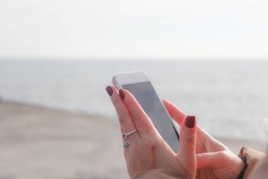 Kumsalda akıllı telefon kullanan güzel bir kadın.