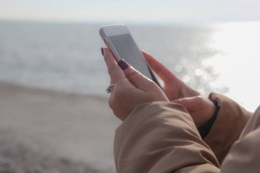 Kumsalda akıllı telefon kullanan güzel bir kadın.