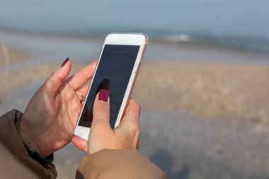 Kumsalda akıllı telefon kullanan güzel bir kadın.