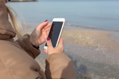 Kumsalda akıllı telefon kullanan güzel bir kadın.