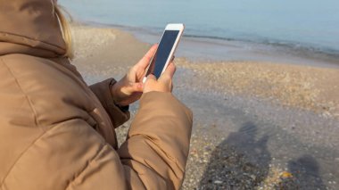Kumsalda akıllı telefon kullanan güzel bir kadın.