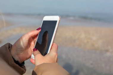 Kumsalda akıllı telefon kullanan güzel bir kadın.