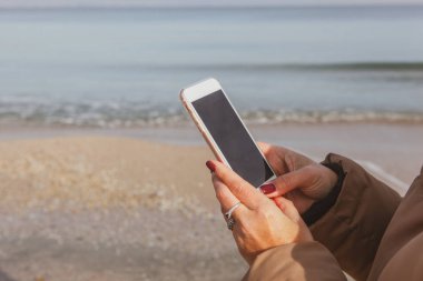 Kumsalda akıllı telefon kullanan güzel bir kadın.
