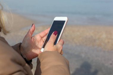 Kumsalda akıllı telefon kullanan güzel bir kadın.