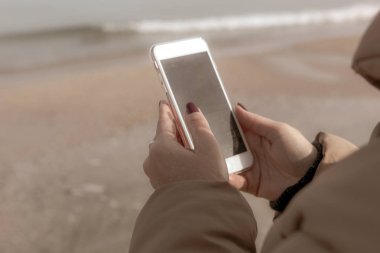 Kumsalda akıllı telefon kullanan güzel bir kadın.