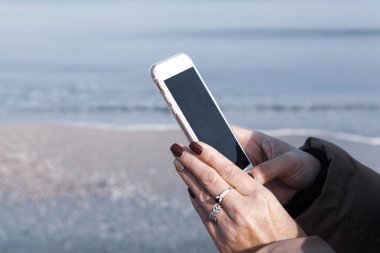 Kumsalda akıllı telefon kullanan güzel bir kadın.
