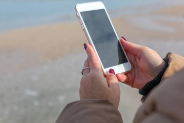Kumsalda akıllı telefon kullanan güzel bir kadın.
