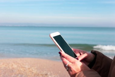 Kumsalda akıllı telefon kullanan güzel bir kadın.