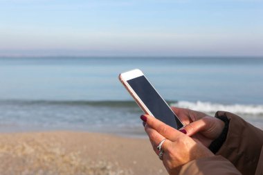 Kumsalda akıllı telefon kullanan güzel bir kadın.