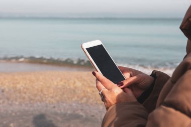 Kumsalda akıllı telefon kullanan güzel bir kadın.