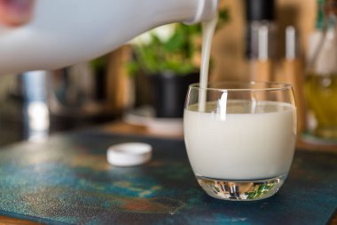 El yağan taze kefir probiotik suya beyaz şişe açık cam mutfak masasında