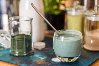 Mutfak masasının üzerinde yeşil spirulina tozu ile portre görünümü taze kefir probiotik içki açık cam içinde karışık