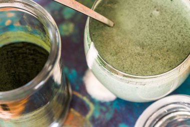 Mutfak masasının üzerinde yeşil spirulina tozu ile portre görünümü taze kefir probiotik içki açık cam içinde karışık