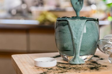 Mutfak masasının üzerinde yeşil spirulina tozu ile portre görünümü taze kefir probiotik içki açık cam içinde karışık
