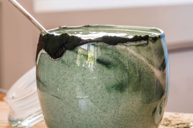 Mutfak masasının üzerinde yeşil spirulina tozu ile portre görünümü taze kefir probiotik içki açık cam içinde karışık