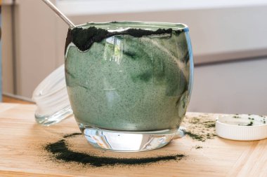 Mutfak masasının üzerinde yeşil spirulina tozu ile portre görünümü taze kefir probiotik içki açık cam içinde karışık