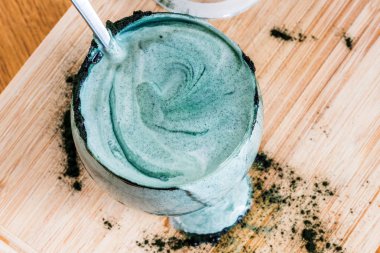 Mutfak masasının üzerinde yeşil spirulina tozu ile portre görünümü taze kefir probiotik içki açık cam içinde karışık