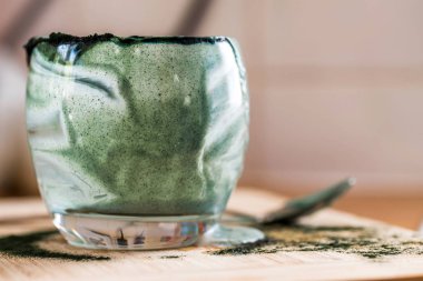 Closeup görünümü cam mutfak masasında içinde kaşık ile yeşil spirulina mamasının taze kefir probiotik içeceği boşalttı