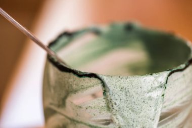 Closeup görünümü cam mutfak masasında içinde kaşık ile yeşil spirulina mamasının taze kefir probiotik içeceği boşalttı