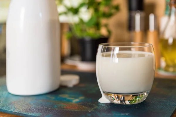 Primer plano ver fresco kéfir probiotik bebida en vidrio transparente y botella blanca en la mesa de la cocina — Foto de Stock