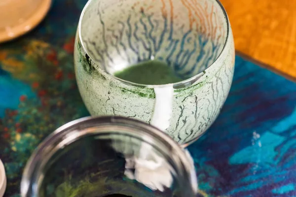 Вид сверху опустошенный бокал свежего кефира пробиотик напиток смешанный с зеленой спирулиной порошок на кухонный стол — стоковое фото