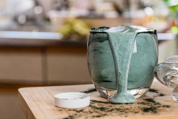 Mutfak masasının üzerinde yeşil spirulina tozu ile portre görünümü taze kefir probiotik içki açık cam içinde karışık