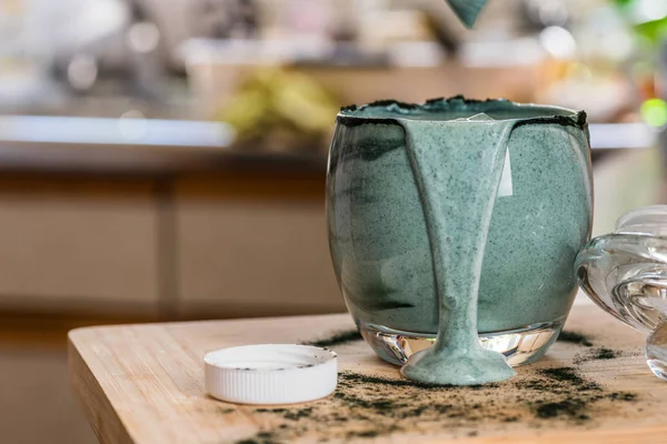 Mutfak masasının üzerinde yeşil spirulina tozu ile portre görünümü taze kefir probiotik içki açık cam içinde karışık