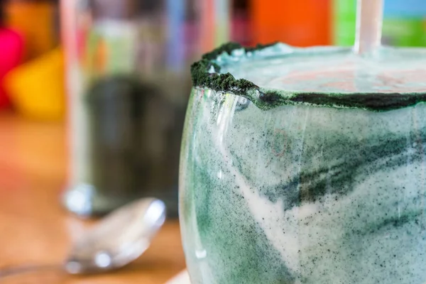 Mutfak masasının üzerinde yeşil spirulina tozu ile portre görünümü taze kefir probiotik içki açık cam içinde karışık