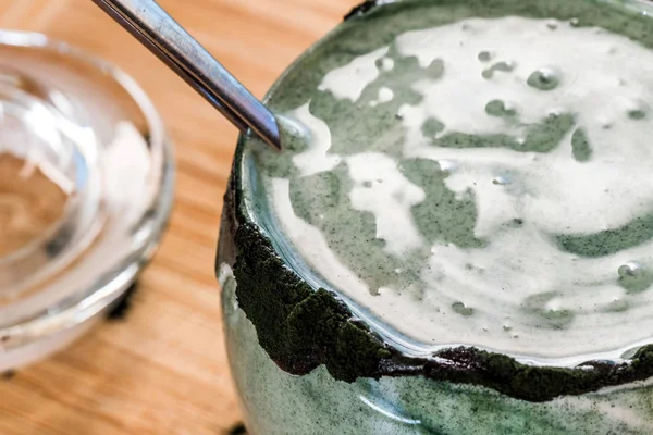 Mutfak masasının üzerinde yeşil spirulina tozu ile portre görünümü taze kefir probiotik içki açık cam içinde karışık — Stok fotoğraf