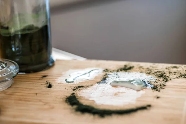 Вид крупным планом свежий кефир пробиотик напиток и зеленый спирулина порошок остатки на деревянной доске после смешивания на кухонном столе — стоковое фото