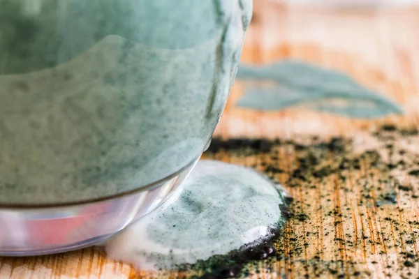 Closeup görünümü taze kefir probiotik içki dolu cam nerede yeşil spirulina tozu mutfak masasında ile karışık oldu ortaya