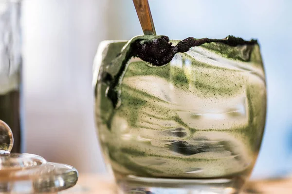 Closeup görünümü cam mutfak masasında içinde kaşık ile yeşil spirulina mamasının taze kefir probiotik içeceği boşalttı