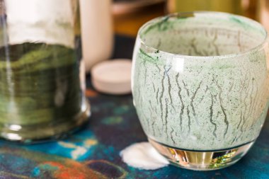 Closeup görünümü cam mutfak masasının üzerinde yeşil spirulina tozu ile karışık taze kefir probiotik içeceği boşalttı